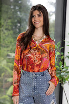 vibrant, long-sleeved button-up blouse with a red, orange, and yellow paisley pattern