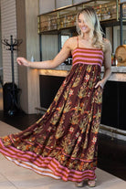 maxi dress with a brown base, pink and orange horizontal stripes on the bodice and hem, and a botanical print in gold, green, and orange across the skirt