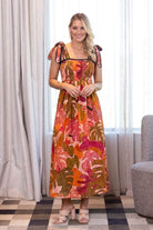sleeveless maxi dress with a vibrant tropical leaf print in orange, pink, and green