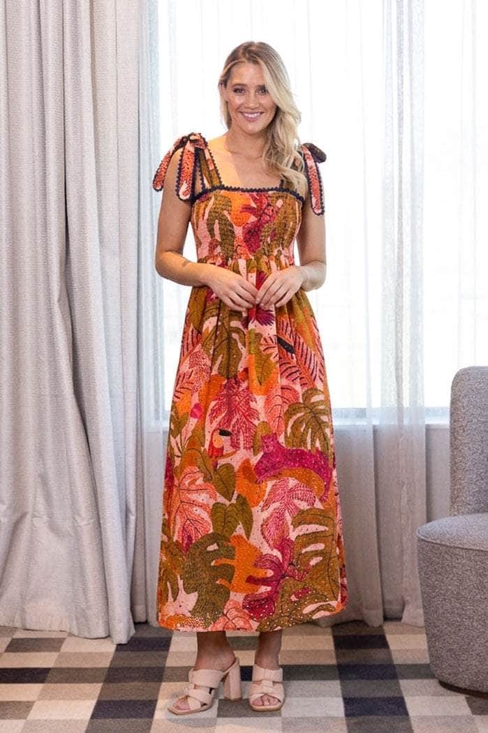 sleeveless maxi dress with a vibrant tropical leaf print in orange, pink, and green